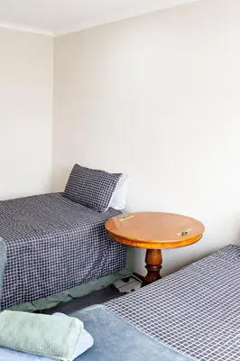 a small room with two beds and a wooden table at Pecan and Lime Inn The Main Den in Pretoria
