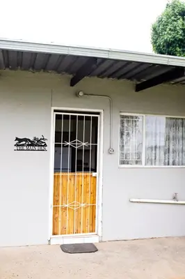 a white house with a door and a window at Pecan and Lime Inn The Main Den in Pretoria