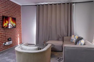 a living room with a couch and a brick wall at Secure 1 Bedroom Apartment in Midrand, Waterfall City - Lock Up and Go - Free WIFI and Parking - 4A Elizabeth Place in Midrand
