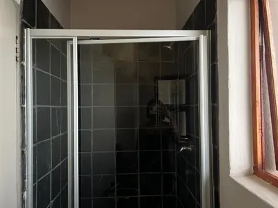 a shower with a glass door in a bathroom at Angelic hut in Midrand