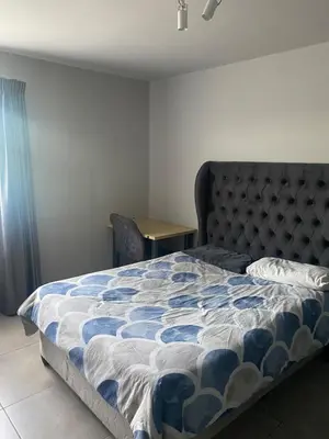 a bedroom with a bed with a blue and white comforter at One Bedroom Apartment at Circa in Pretoria