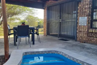 a patio with a table and chairs and a pool at Finch Nest in Marloth Park