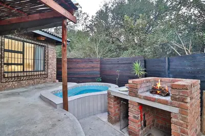 a backyard with a brick fireplace and a swimming pool at Finch Nest in Marloth Park