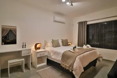 a bedroom with a bed with a desk and a window at Finch Nest in Marloth Park