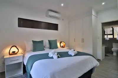a bedroom with a large white bed with towels on it at Krokodil Rus in Marloth Park