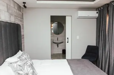 a bedroom with a bed and a sink and a mirror at La Grace in Kempton Park