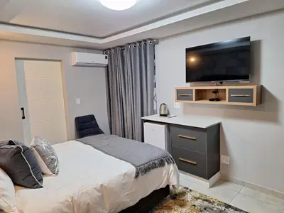 a bedroom with a bed and a flat screen tv at La Grace in Kempton Park