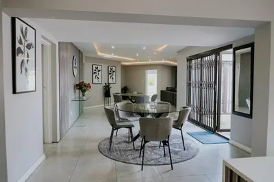 a dining room with a glass table and chairs at La Grace in Kempton Park