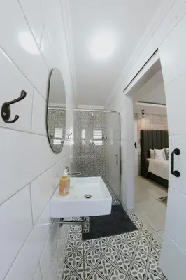 a white bathroom with a sink and a mirror at La Grace in Kempton Park