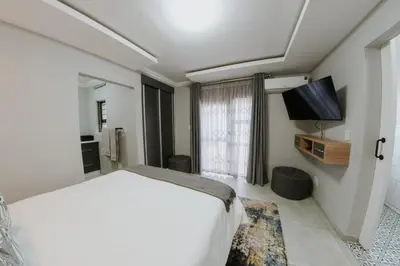 a bedroom with a large white bed and a flat screen tv at La Grace in Kempton Park