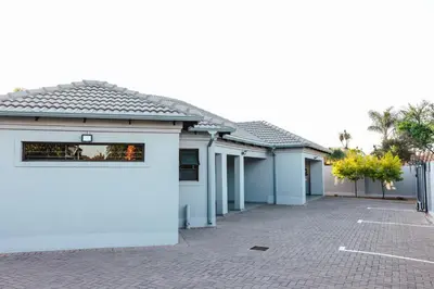 a row of white buildings with a parking lot at La Grace in Kempton Park