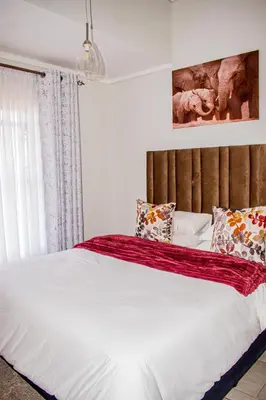 a bedroom with a large bed with a red blanket on it at Modern Retreat in Pretoria with Lagoon Pool & Gym in Pretoria