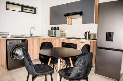 a kitchen with a table and chairs in a kitchen at Modern Retreat in Pretoria with Lagoon Pool & Gym in Pretoria