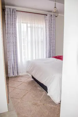 a bedroom with a bed and a large window at Modern Retreat in Pretoria with Lagoon Pool & Gym in Pretoria