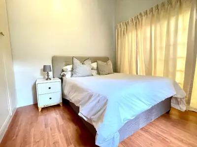 a bedroom with a white bed with a nightstand and a window at BB Hers Cheesy in Midrand