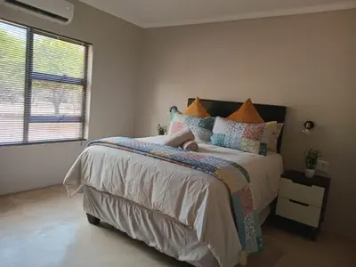 a bedroom with a bed and a large window at Taíta Lodge in Marloth Park