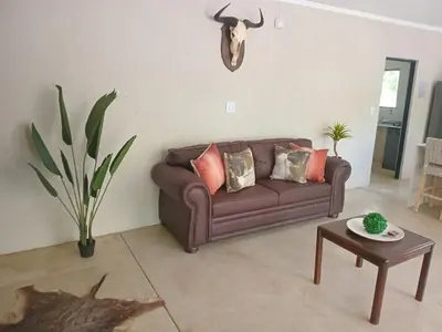 a living room with a brown couch and a table at Taíta Lodge in Marloth Park