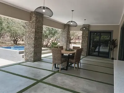 a dining room with a table and chairs and a pool at Taíta Lodge in Marloth Park