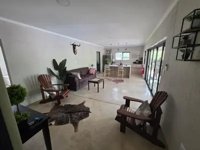 a living room with a couch and a table and chairs at Taíta Lodge in Marloth Park