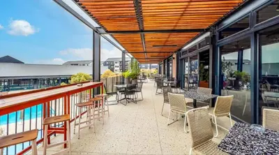 a patio with tables and chairs on a balcony at Modern Retreat in Waterfall Midrand with Pool & Restaurant in Kyalami