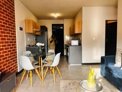 a woman taking a picture of a kitchen and a living room at Modern Retreat in Waterfall Midrand with Pool & Restaurant in Kyalami