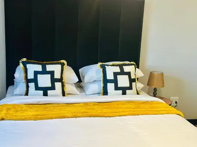 a bed with blue and white pillows on it at Modern Retreat in Waterfall Midrand with Pool & Restaurant in Kyalami