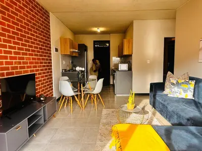a living room with a couch and a brick wall at Modern Retreat in Waterfall Midrand with Pool & Restaurant in Kyalami