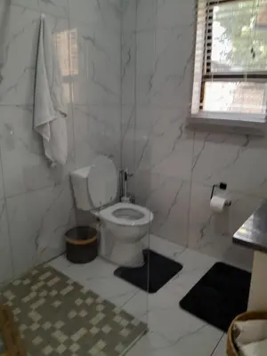 a white bathroom with a toilet and a window at Transit Haven - 2 Bed Retreat in Kempton Park