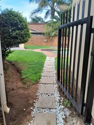 a gate to a garden with a stone walkway at Transit Haven - 2 Bed Retreat in Kempton Park