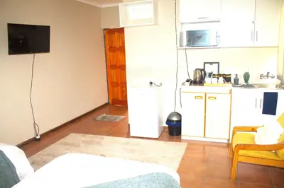 a living room with a small kitchen and a kitchen at Ador Lodges in Midrand
