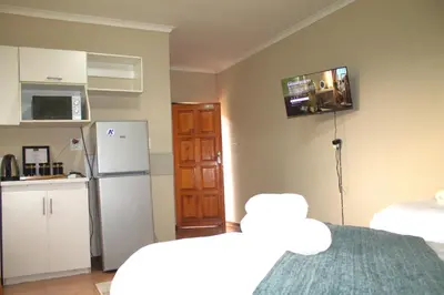 a small kitchen with a refrigerator and a microwave at Ador Lodges in Midrand