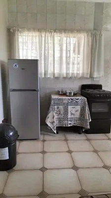 a kitchen with a table and a refrigerator and a stove at Ador Lodges in Midrand