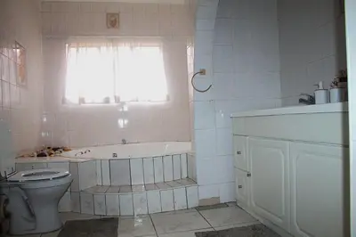 a bathroom with a tub and a toilet and a window at Ador Lodges in Midrand