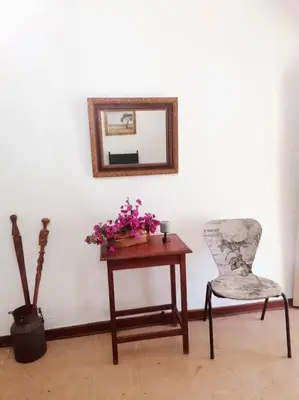 a table with a chair and a mirror and flowers at Church Mouse House in Pilgrimʼs Rest