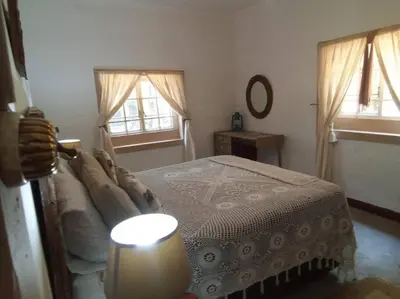 a bedroom with a bed and a lamp and two windows at Church Mouse House in Pilgrimʼs Rest