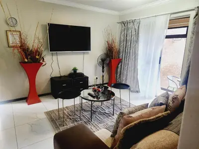 a living room with a couch and a tv at Olympia in Pretoria