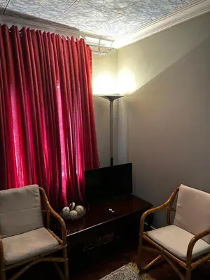 a living room with a red curtain and two chairs at Garden Studio in Waterkloof Ridge in Pretoria
