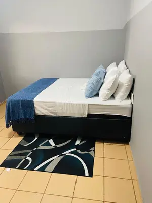 a bed with pillows and a rug in a room at KINGs' PALACE GUESTHOUSE in Ermelo
