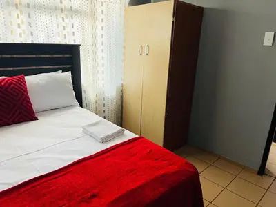 a bedroom with a bed with a red blanket at KINGs' PALACE GUESTHOUSE in Ermelo