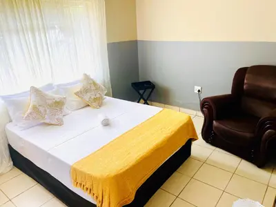 a bedroom with a bed and a chair at KINGs' PALACE GUESTHOUSE in Ermelo