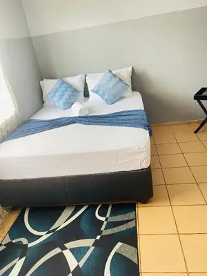 a bed with blue pillows on it in a room at KINGs' PALACE GUESTHOUSE in Ermelo