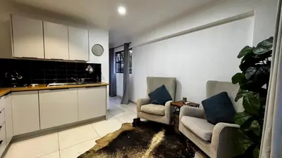 a living room with two chairs and a kitchen at Micro Urban Oasis 1 in Pretoria