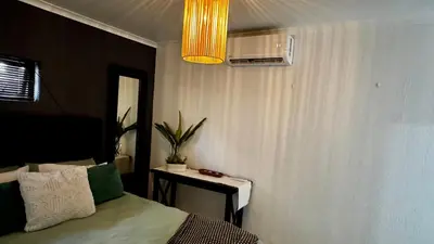 a bedroom with a bed and a table and a light at Micro Urban Oasis 1 in Pretoria