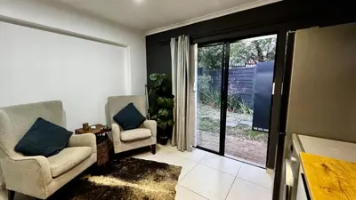 a living room with two chairs and a sliding glass door at Micro Urban Oasis 1 in Pretoria