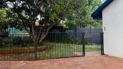 a black fence with a tree in a yard at Micro Urban Oasis 1 in Pretoria