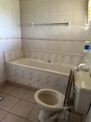 a bathroom with a toilet and a bath tub at Okgethilwe Lodge in Sabie