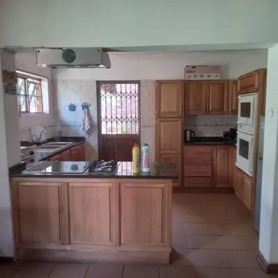 a kitchen with wooden cabinets and a counter top at Okgethilwe Lodge in Sabie