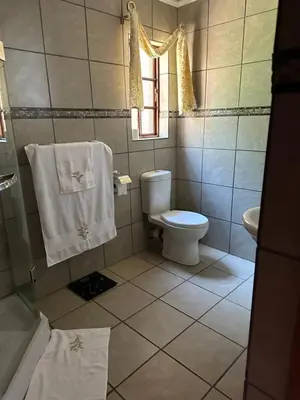 a bathroom with a toilet and a window and towels at Okgethilwe Lodge in Sabie