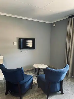 a room with two blue chairs and a table and a tv at Mercy House Lodge in Northam