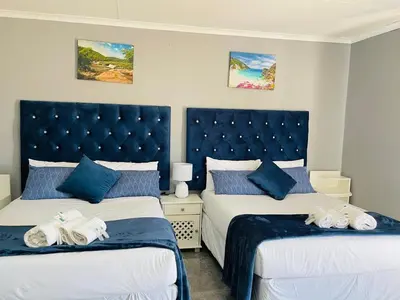 two beds in a bedroom with blue and white at Mercy House Lodge in Northam